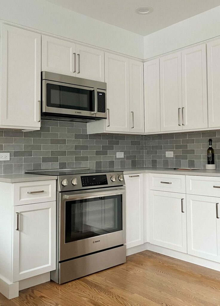 white kitchen with soffit above upper cabinetry, gray backsplash tile