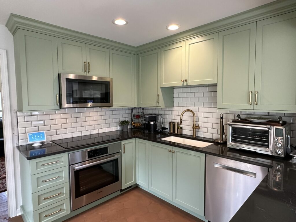 soft green cabinetry in u-shaped kitchen with white subway tile