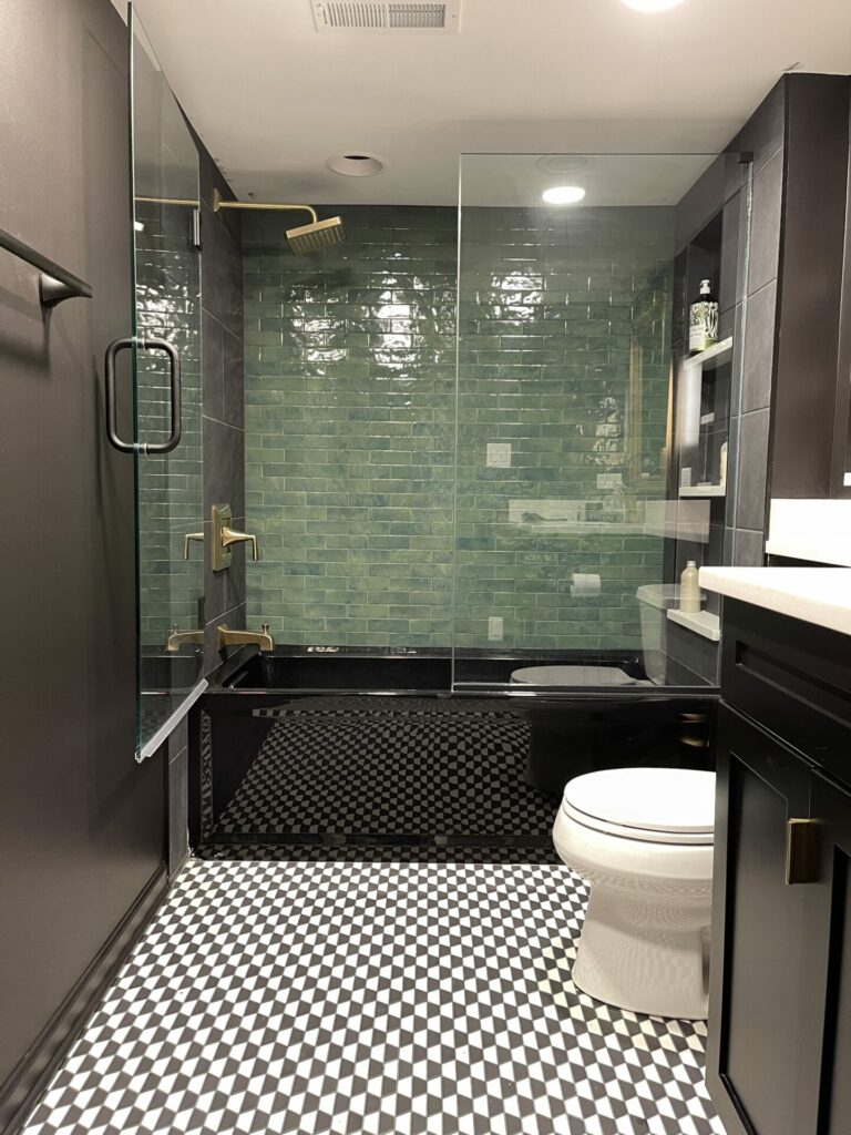 black bathroom with green shower tile and shower doors