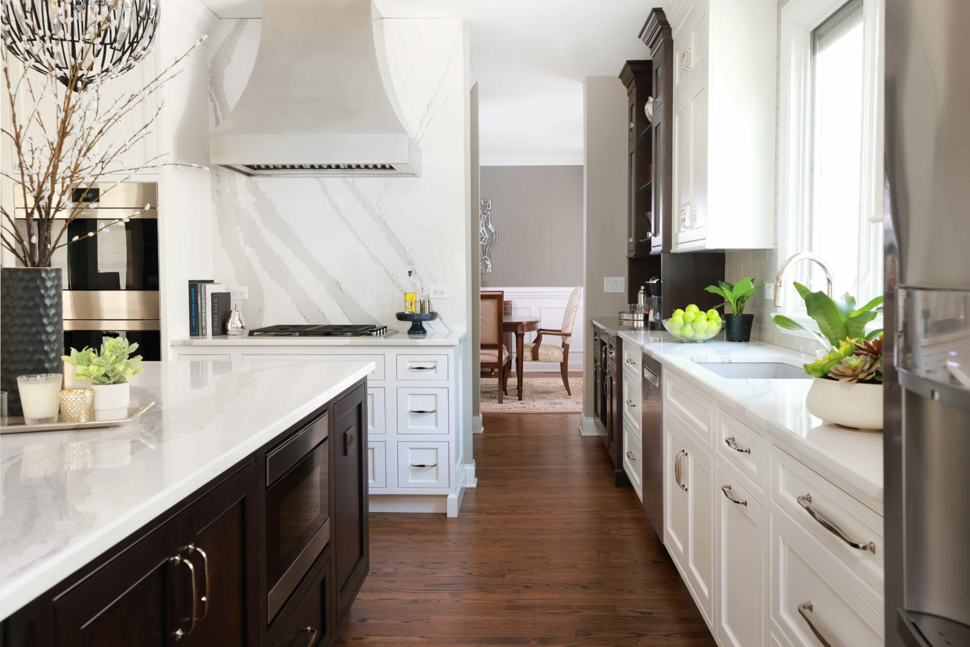 white painted kitchen with slab backsplash and metal hood pairs with dark stained island
