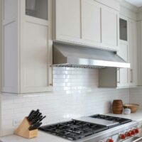 Warm white kitchen cabinets with a stainless steel hood