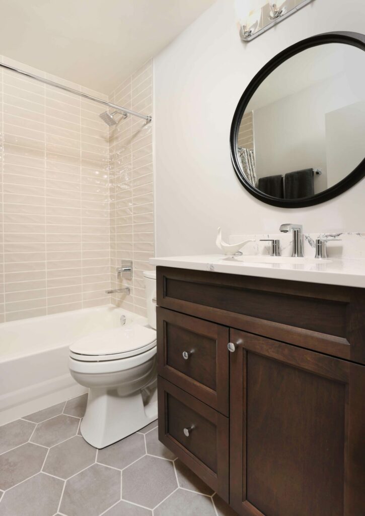 condo bathroom with dark cabinetry and hexagon floor tiles and horizontal tile in tub