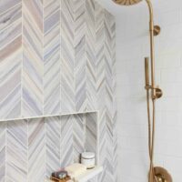 Chevron tile in shower with niche and gold shower fixture