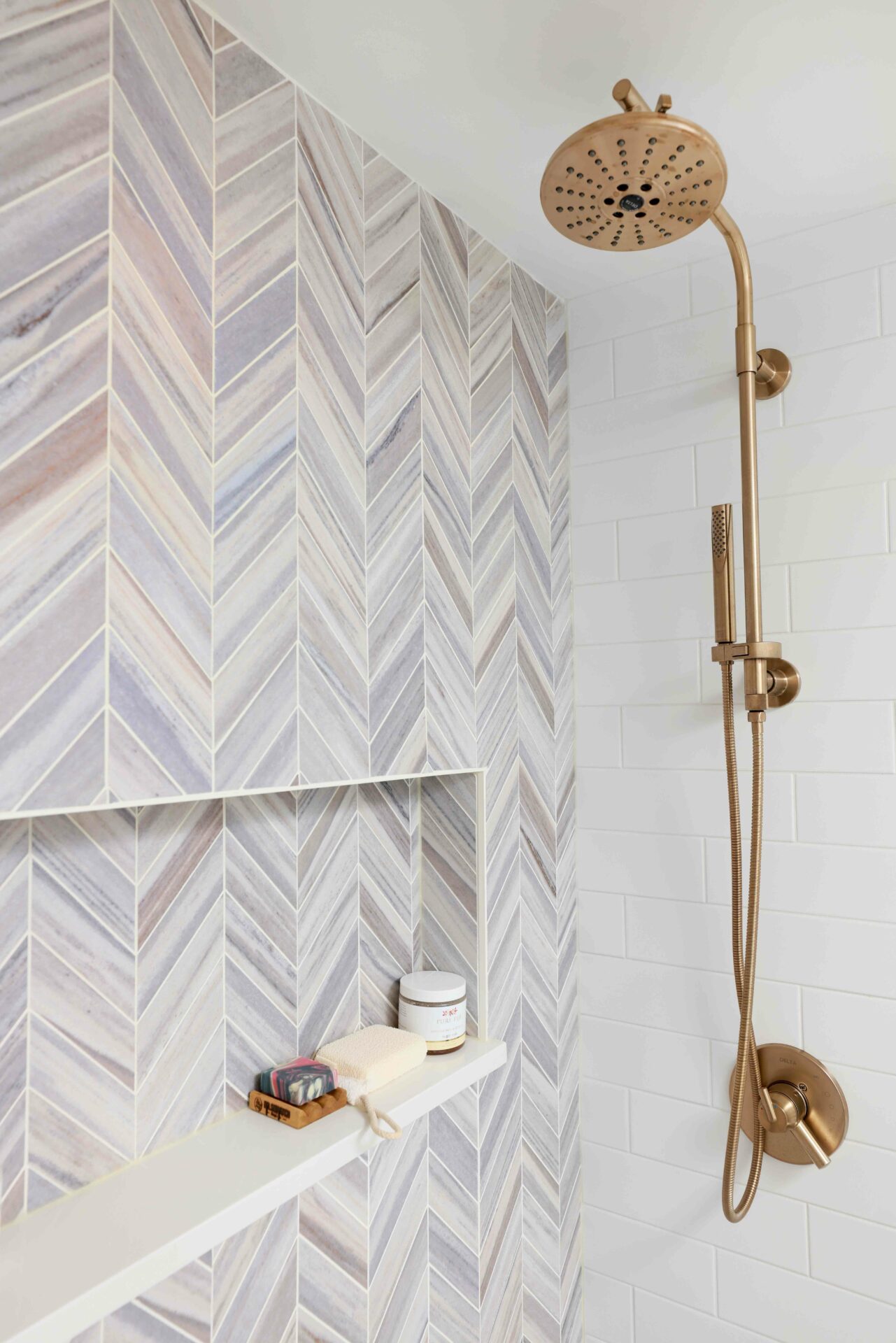 Chevron tile in shower with niche and gold shower fixture