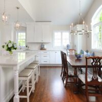 white kitchen addition with large island and stools and dining table with window bench seating