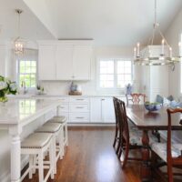 white kitchen addition with large island and stools and dining table with window bench seating