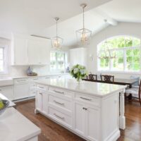 white kitchen addition with island and kitchen table with window seating bench