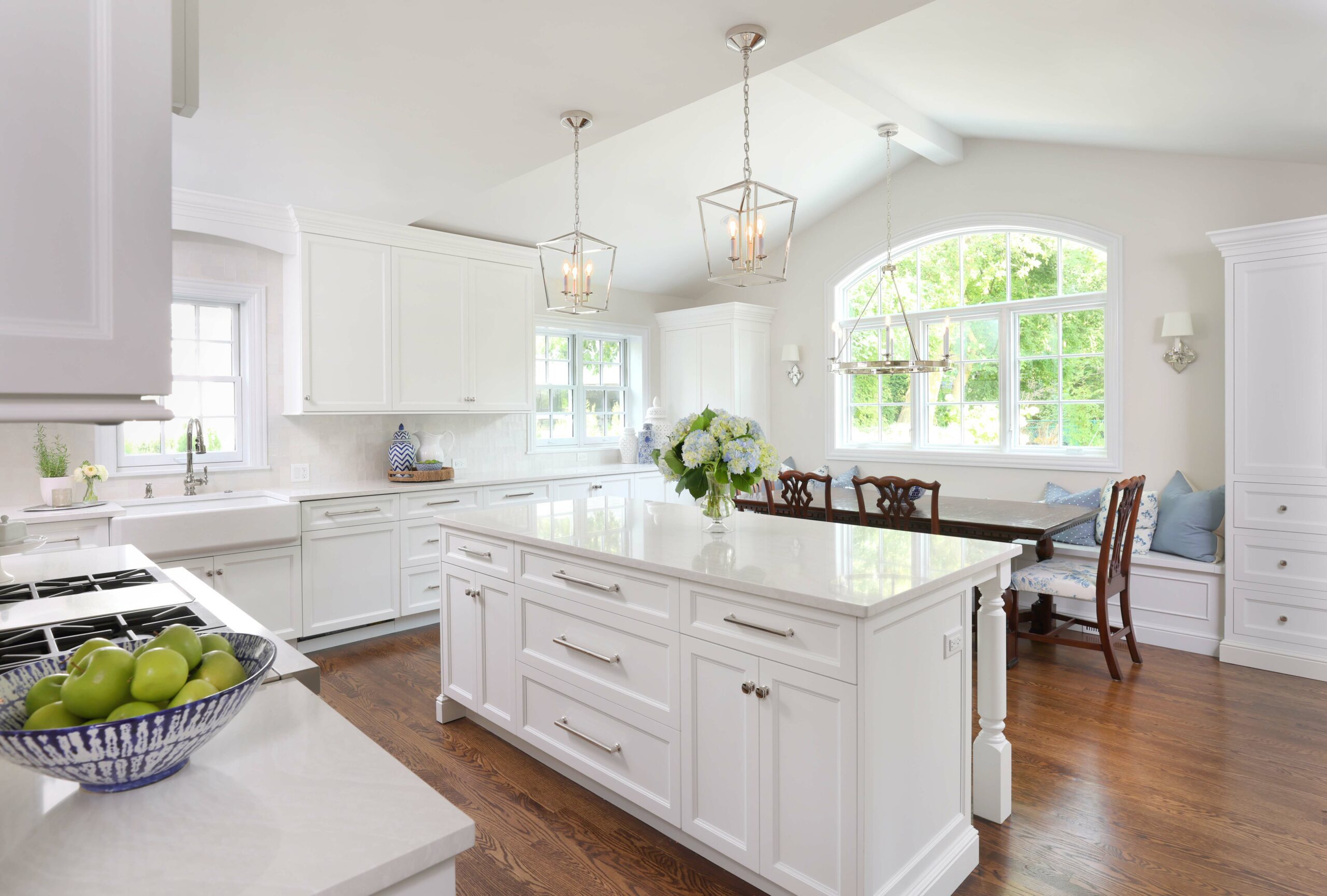 white kitchen addition with island and kitchen table with window seating bench