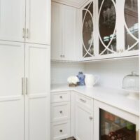white kitchen beverage chiller and upper cabinets with decorative glass fronts