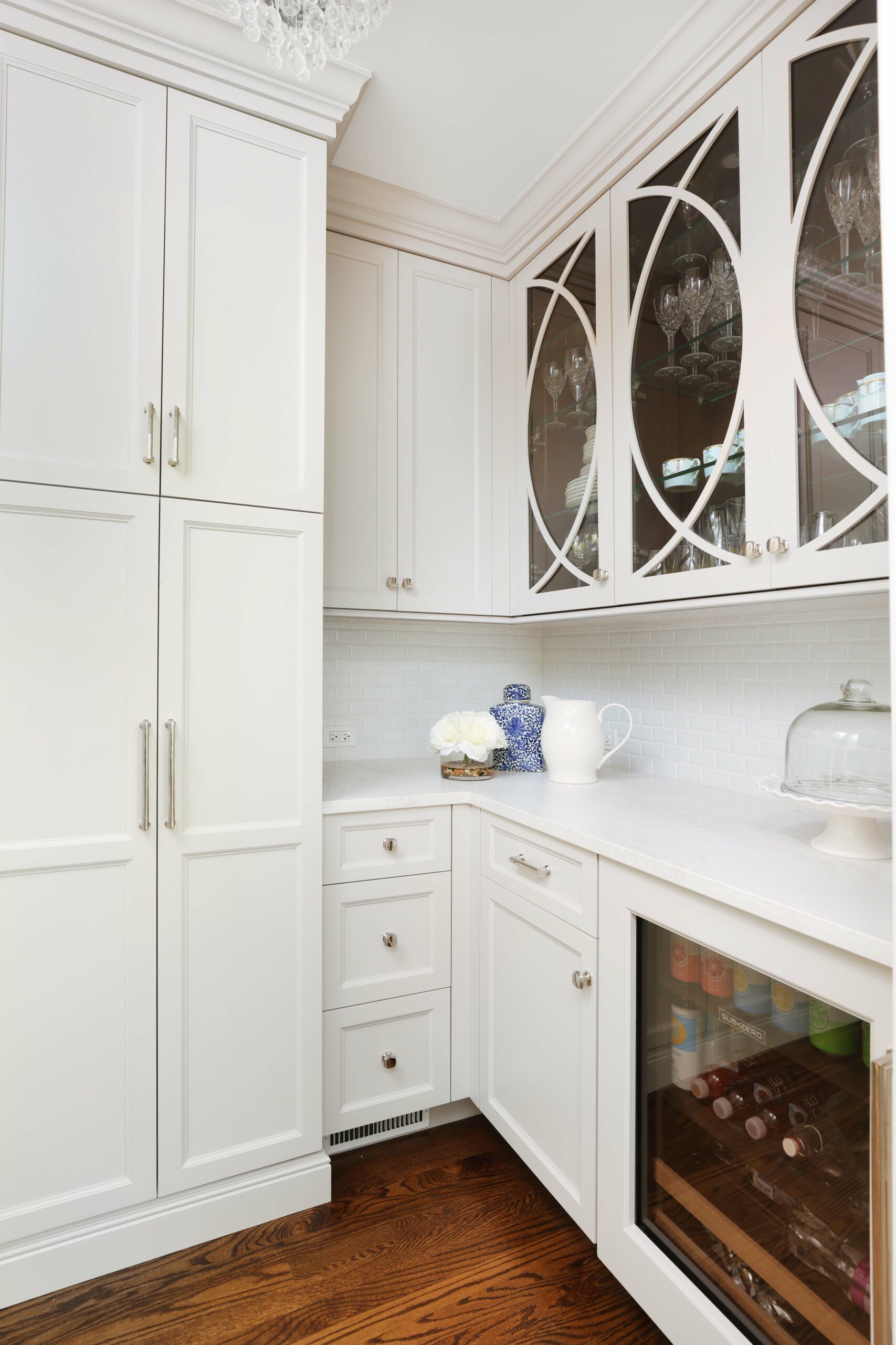 white kitchen beverage chiller and upper cabinets with decorative glass fronts