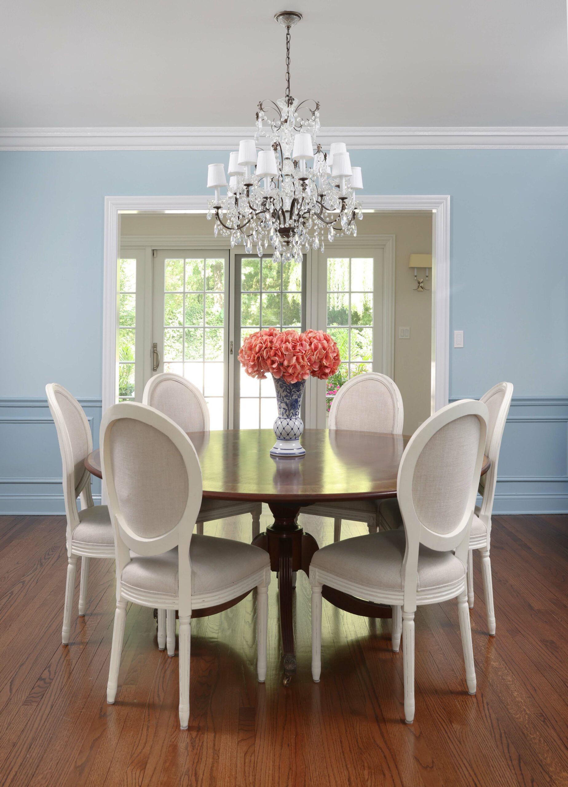 blue dining room with chandelier, wall moulding, hardwood floors