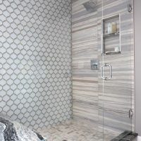 framless shower with 3 types of patterned tile on walls and shower floor, with niche and rain showerhead
