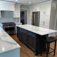 White painted cabinets with a shaker style door, dark stained island and quartz countertops