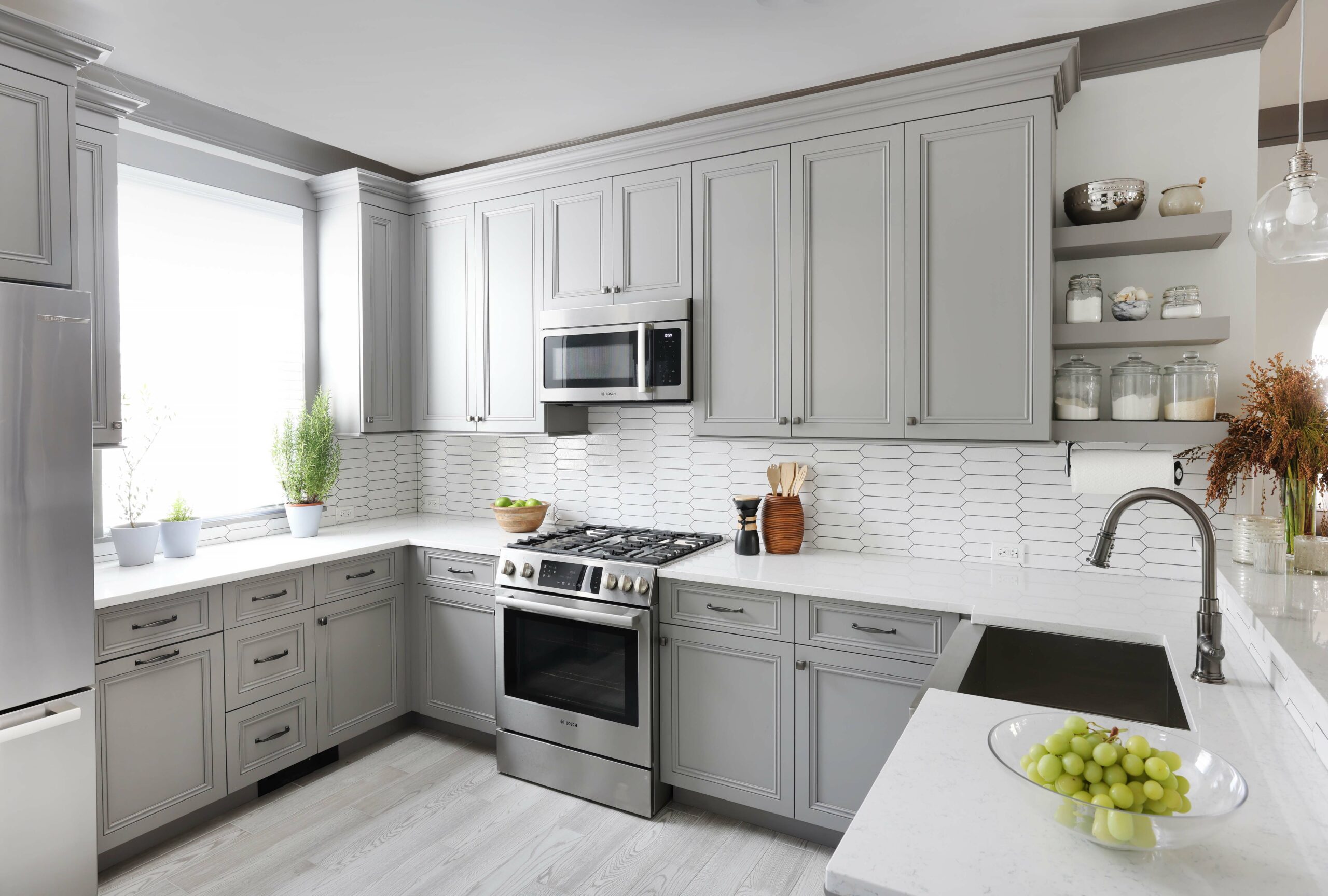 gray painted maple cabinets and open shelves in kitchen with white geometric backsplash