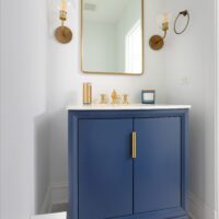 deep blue single vanity and gold fixtures in powder room