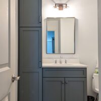 basement bathroom with gray cabinets and storage tower