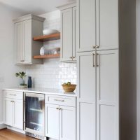 soft white cabinetry with open wooden shelving above beverage center in kitchen