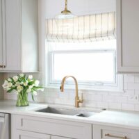 Light gray kitchen cabinets with gold tone faucet