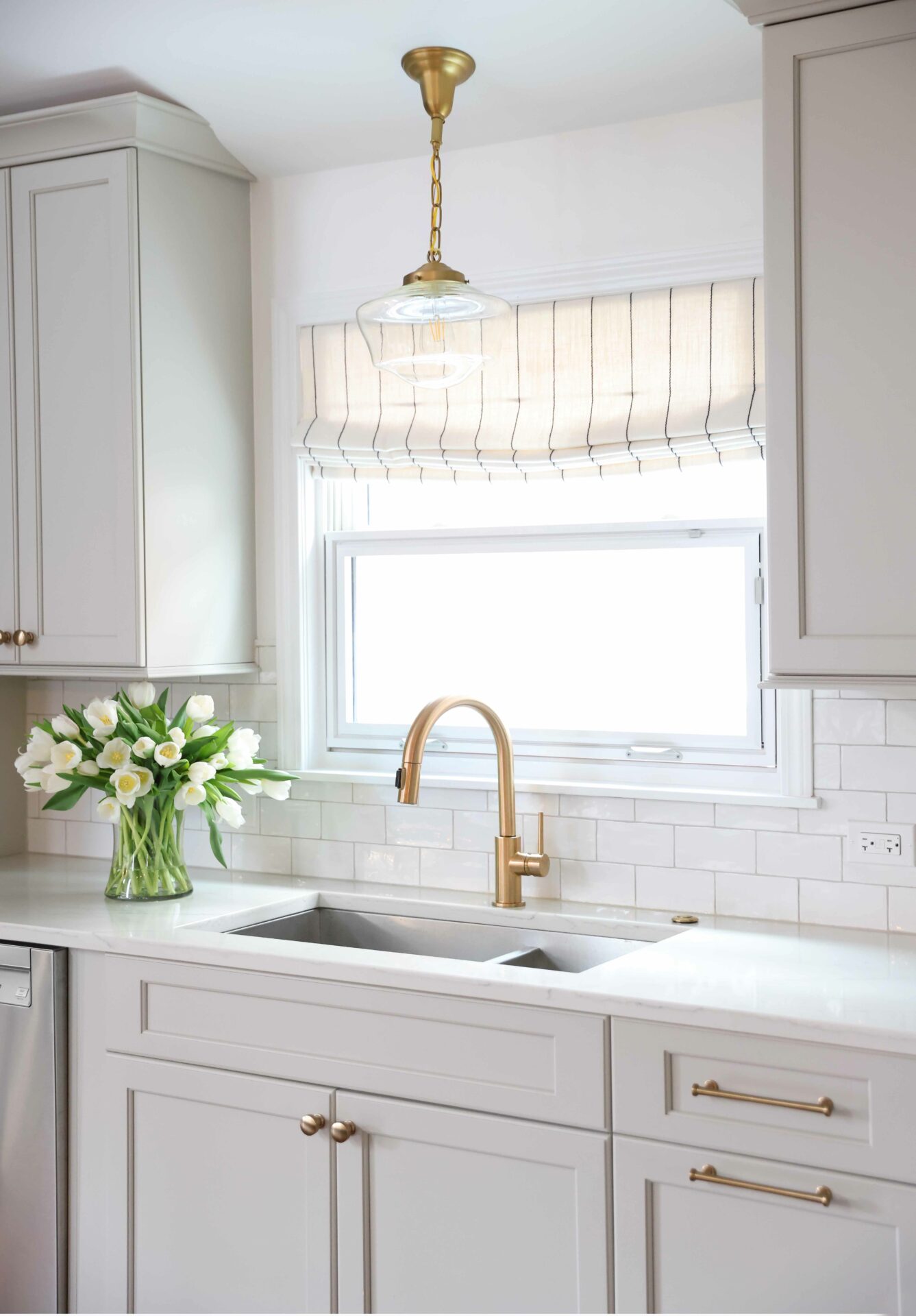 Light gray kitchen cabinets with gold tone faucet