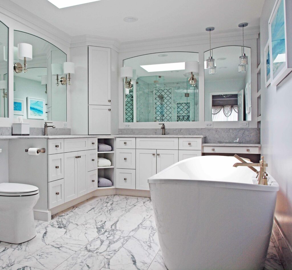 All white bathroom with framed arched mirrors, freestanding tub, and skylight
