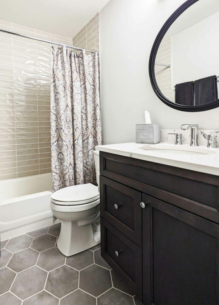 full bathroom with dark vanity, hexagon floor tiles and shower-tub combo