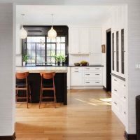 hardwood flooring in white kitchen with dark island and black window