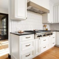wood hood with contrasting band in white kitchen with dark countertops