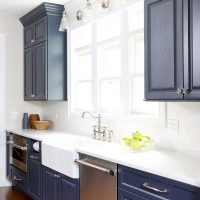 Blue kitchen cabinets with apron front sink and white backsplash tile