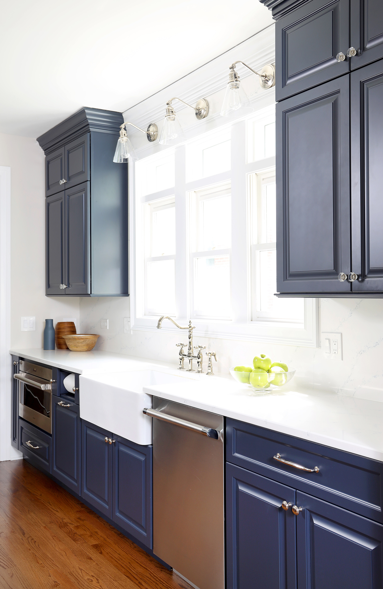 Blue kitchen cabinets with apron front sink and white backsplash tile