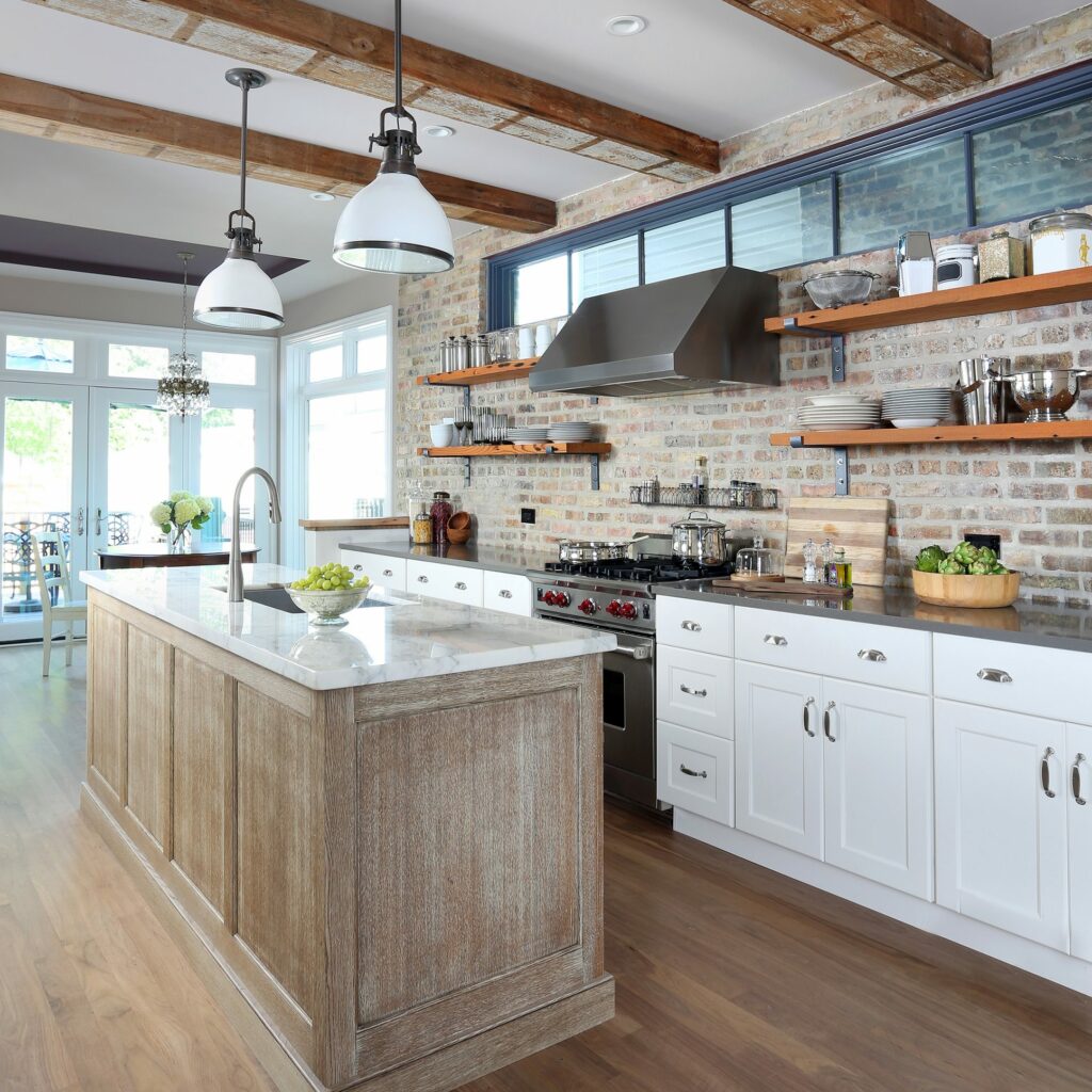 White kitchen with distressed island and open shelving with exposed brick