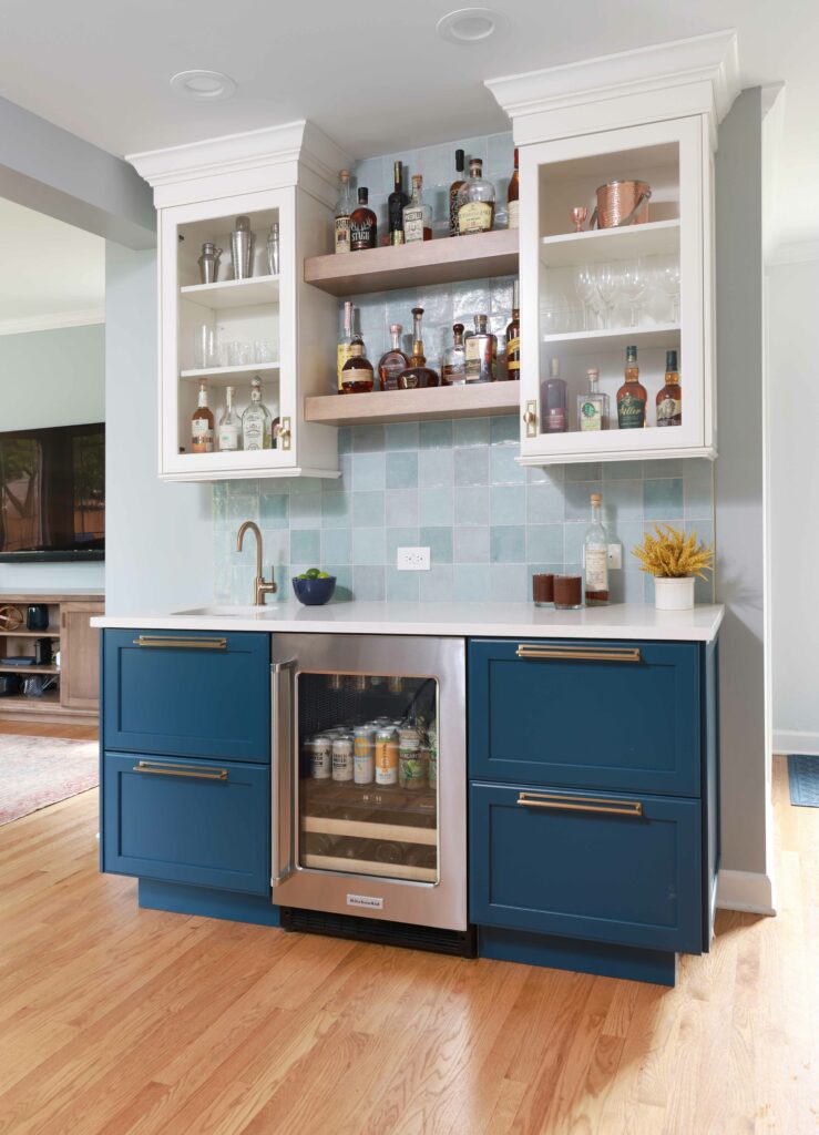 home wet bar with blue cabinets, floating shelves, and blue backsplash tile